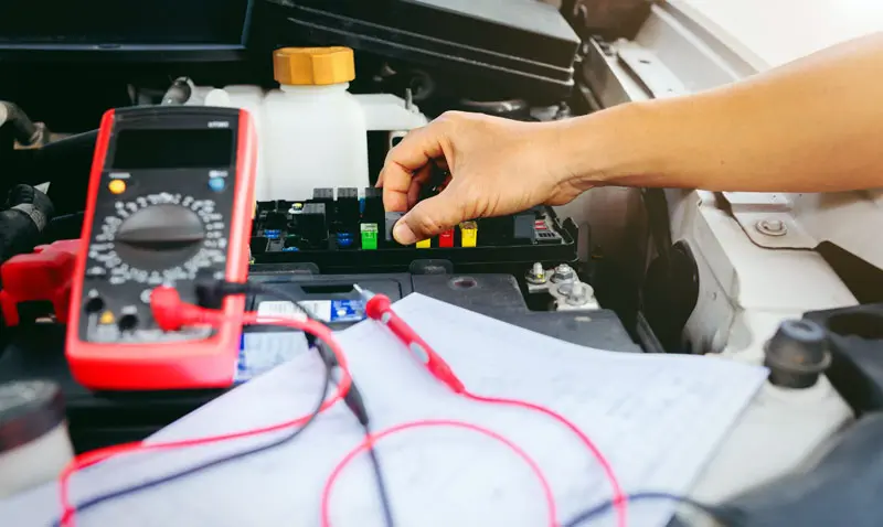 fuses-being-checked Mechanic checking fuses under a cars hood